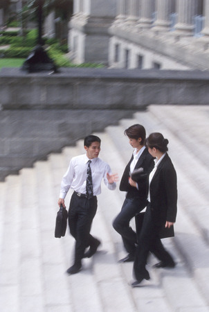 Three executives walking down a flight of stepsの写真素材