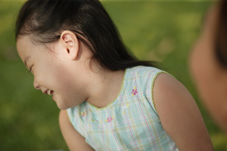 Young girl laughing, mother looking onの写真素材