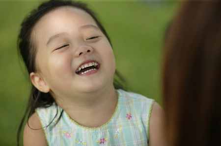 Young girl laughing, mother looking onの写真素材