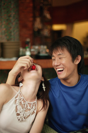 Young man feeding young woman a cherryの写真素材