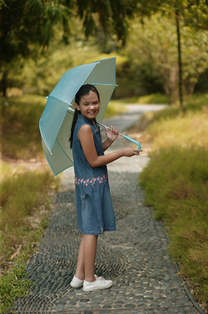 Young girl holding an umbrella, looking over shoulderの写真素材