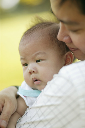 Father carrying baby, over the shoulder view.の写真素材