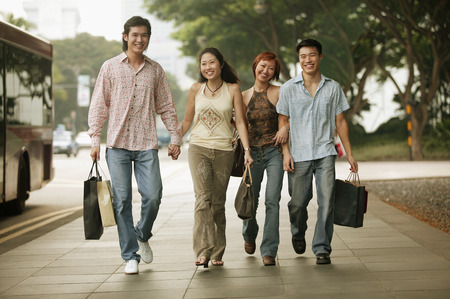 Couples walking together, carrying shopping bagsの写真素材