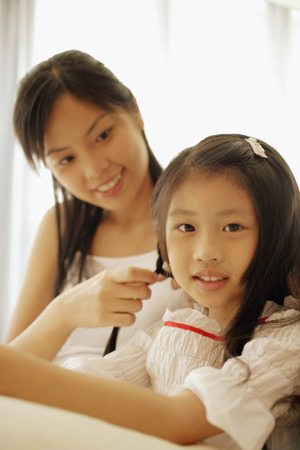 Mother  braiding her daughter's hair.の写真素材