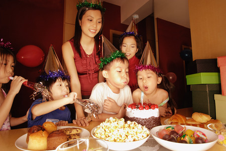 Young boy blowing out candles on a cakeの写真素材