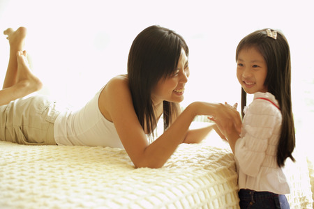 Mother and daughter in bedroom, face to faceの写真素材