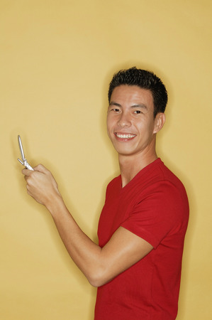 Young man holding mobile phone, looking at cameraの写真素材