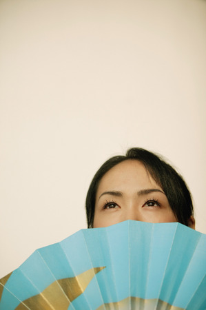 Young woman, face obscured by fanの写真素材
