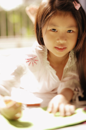 Young girl looking at camera, holding a penの写真素材