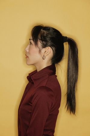 Young woman, side view, yellow backgroundの写真素材