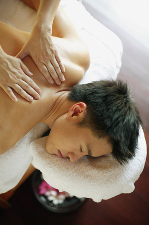 Young man receiving back massage, eyes closedの写真素材