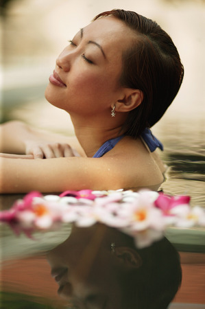 Young woman, at edge of swimming pool, eyes closedの写真素材