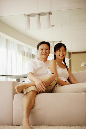 Couple sitting down side by side, looking at cameraの写真素材