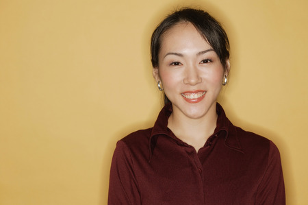 Young woman, smiling, yellow backgroundの写真素材