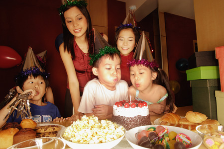Young boy blowing out candles at a birthday party.の写真素材