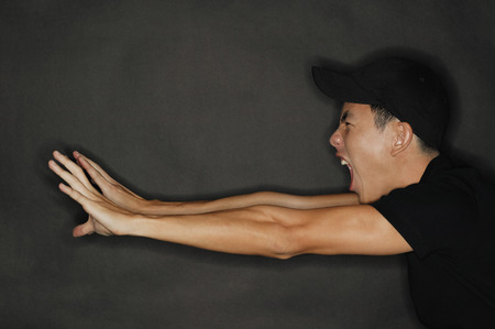 Young man reaching forward, stretching, mouth openの写真素材