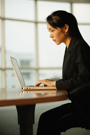 Young woman sitting at desk, using laptopの写真素材