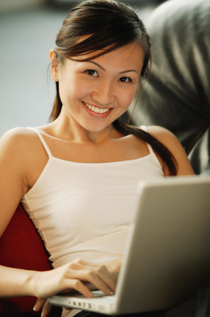 Young woman on sofa, looking at camera, smilingの写真素材