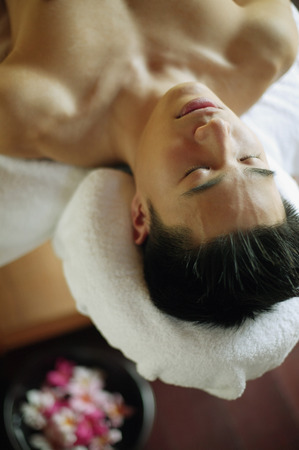 Young man lying down on massage tableの写真素材