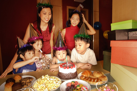 Young girl blowing out candles at a birthday party.の写真素材