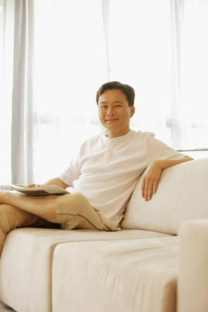 Man sitting on sofa, looking at cameraの写真素材