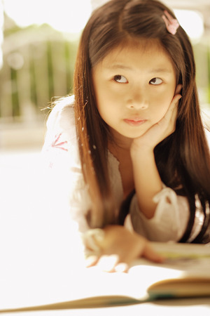 Young girl with hand on chin, looking awayの写真素材