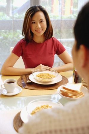 Couple sitting across from each other, breakfast in front of them.の写真素材