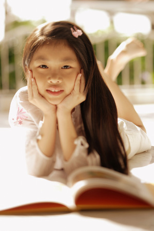 Young girl with hands on chin, looking at cameraの写真素材
