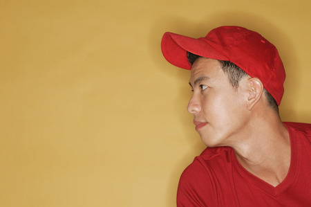 Young man wearing a red cap, against a yellow backgroundの写真素材