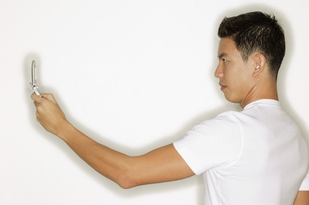 Young man holding mobile phone, side viewの写真素材