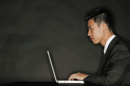 Young man using laptop, side viewの写真素材