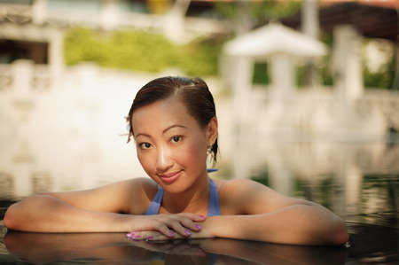 Young woman at the edge of a pool, looking at cameraの写真素材