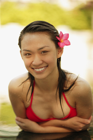 Young woman in a  swimming pool, flower in hairの写真素材