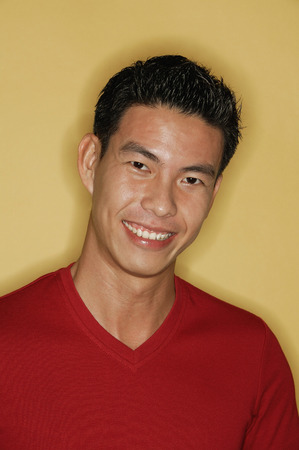 Young man looking at camera, yellow backgroundの写真素材