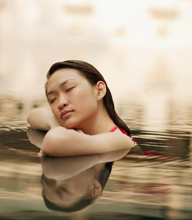 Young woman, at edge of swimming pool, eyes closedの写真素材