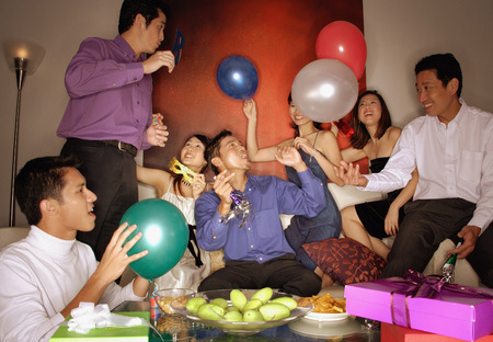 Group of friends having a party at home, holding balloonsの写真素材