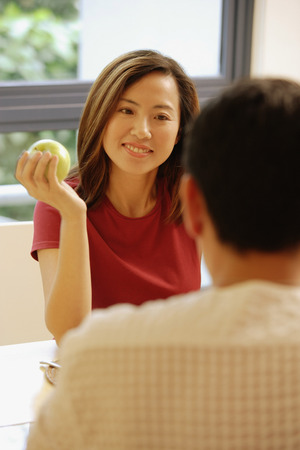 Couple facing each other, woman holding an appleの写真素材
