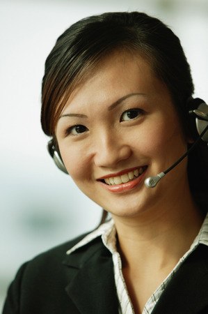 Young woman wearing hands-free device, looking at cameraの写真素材