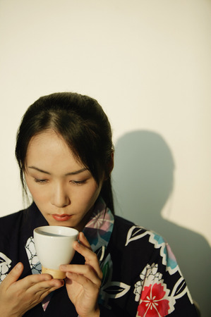 Young woman in kimono holding a tea cupの写真素材