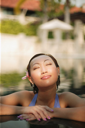 Young woman, at edge of swimming pool, eyes closedの写真素材