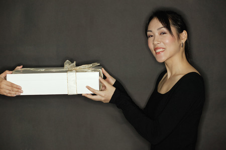 Young woman holding a gift, black backgroundの写真素材