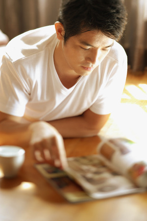 Young man reading magazineの写真素材