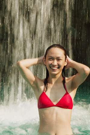 Young woman in swimming pool, water cascading on herの写真素材