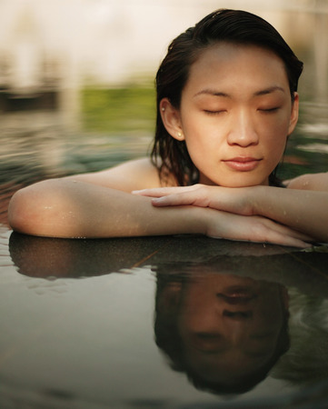 Young woman, at edge of swimming pool, eyes closedの写真素材