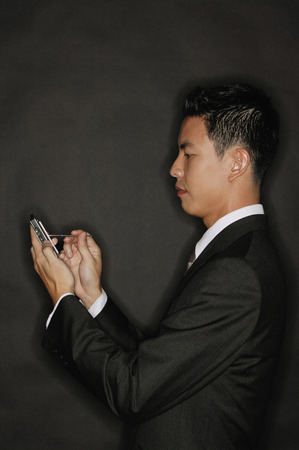 Young man using PDA, standing in profileの写真素材