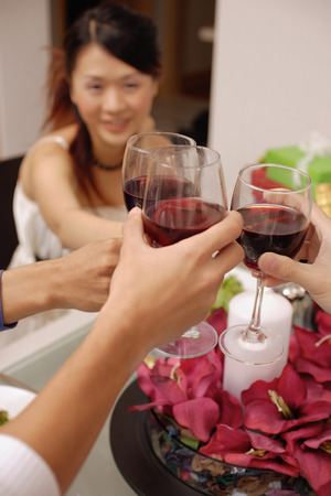 Friends raising wine glass, toasting across tableの写真素材