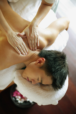 Young man receiving back massageの写真素材