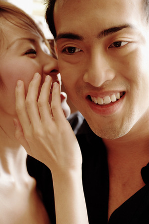 Young woman whispering to young man
