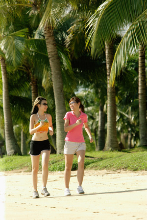 Women jogging along beach, side by sideの写真素材