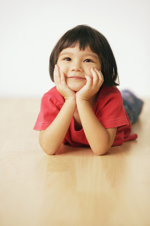 Young girl smiling with hands on chinの写真素材